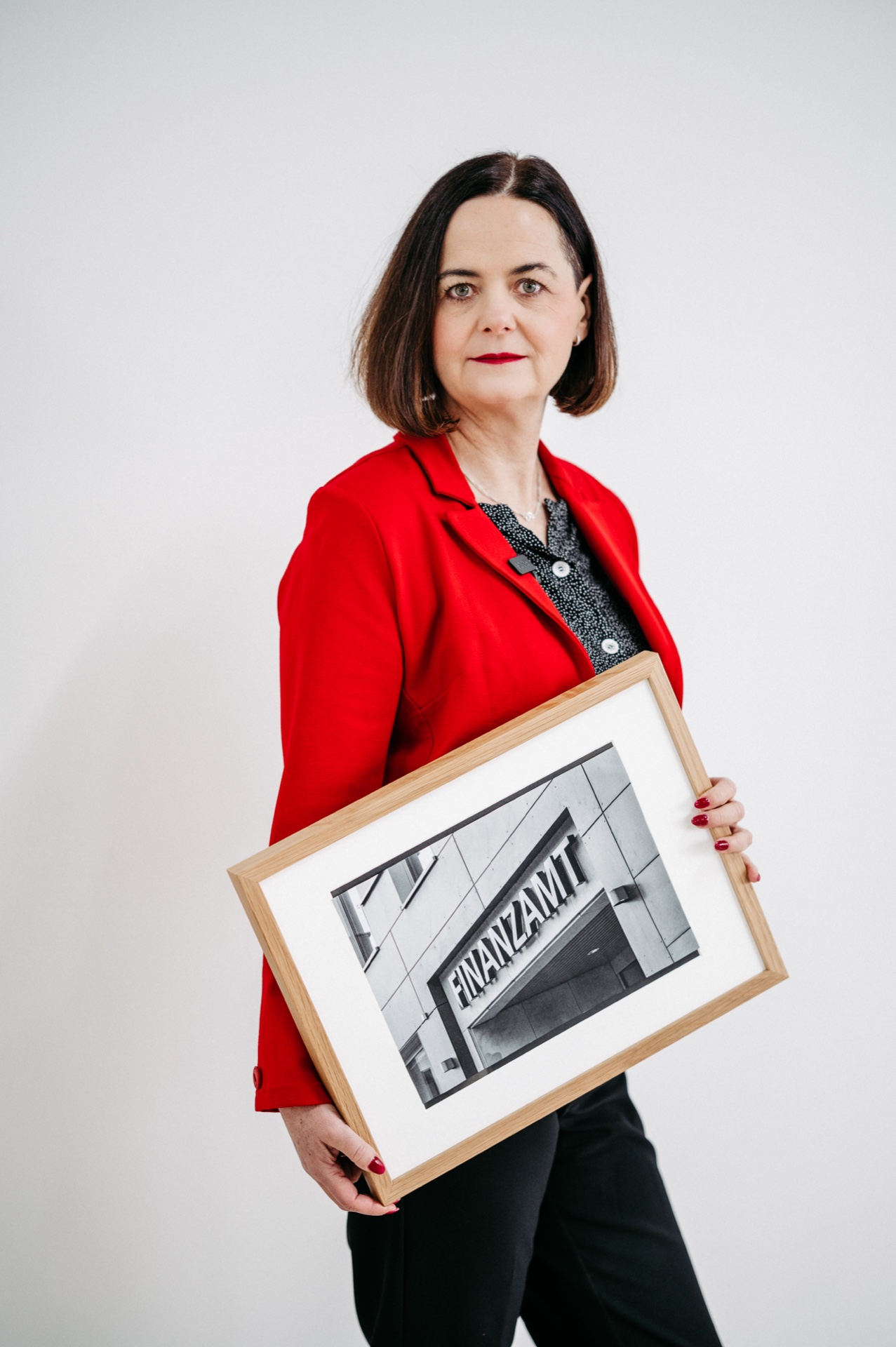 Ute Wagner hält ein gerahmtes Foto des Finanzamts
